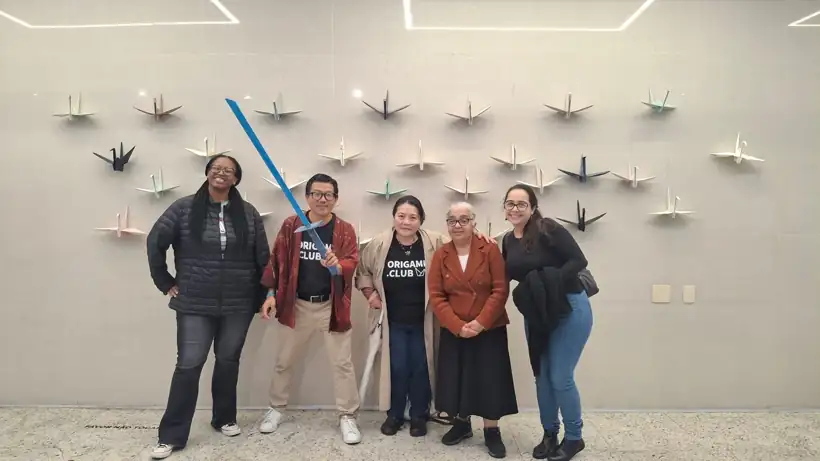 Membros da Tribo do Origami.club diante de uma parede de tsurus